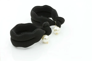 Detail of wave-shaped black flocked hair accessories featuring large white pearl pendants