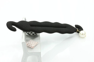 Detail of black sponge hair bun maker featuring wave shape and large pearl ornament