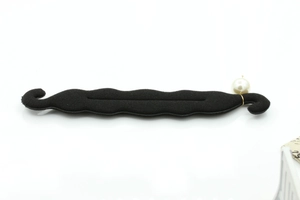 Detail of a flexible black foam hair bun maker with a single white pearl accent