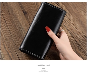 Detail view of a long black leather wallet with white contrast stitching and many card slots