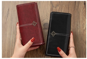 Close-up of vintage leather wallets with white stitching and gold flower hardware