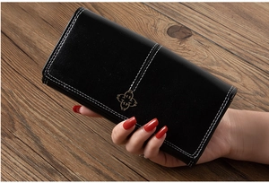 Detail of black leather wallet featuring contrast stitching and floral metal clasp