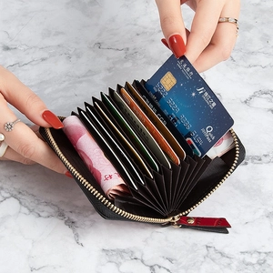 Mini black crocodile pattern accordion card holder with red zipper pull on marble background