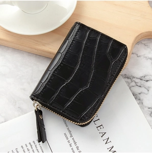 Macro view of black crocodile pattern wallet with gold zipper on a wooden table