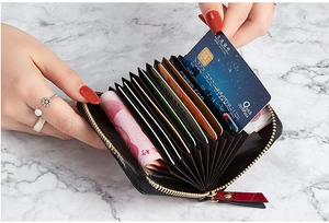 Detail of hand placing cards into a black crocodile texture multi-slot zip card holder