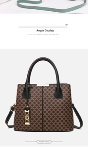 Detailed view of brown vintage monogram handbag with gold charms and black leather handles