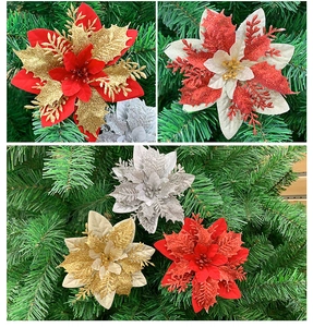 Close-up of glitter-coated artificial Christmas poinsettia flowers on a pine tree