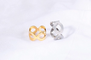 Nahaufnahme goldener und silberner Ringe mit Ziffer 8 Design auf weißem Stoff