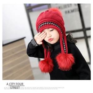Cute red kids knitted hat with fluffy pom-poms and warm ear flaps for winter comfort