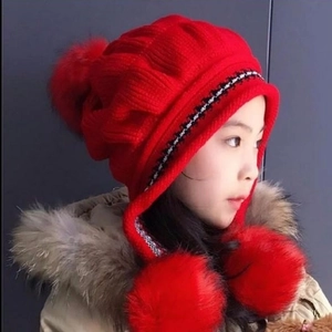 Cute red knit baby hat with earflaps and three fluffy pom poms for winter warmth