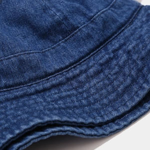 Gros plan des coutures renforcées et du tissu denim délavé sur le bord du bob chapeau