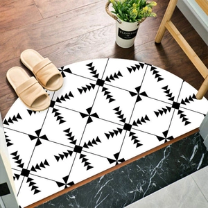Semi-circular entryway mat with black and white geometric patterns on a wooden floor