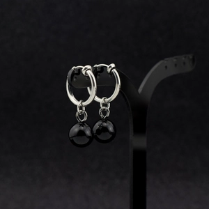 Macro shot of silver metal hoop clip-on earrings with polished black spherical charms