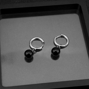 Detail of silver stainless steel hoop earrings with glossy black bead pendants