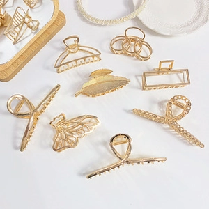 Detailed flat lay of golden metallic hair claws in leaf and butterfly hollow designs