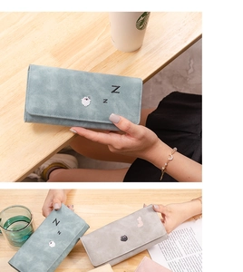 Detailed view of long wallets in pastel colors with cat embroidery on wood background
