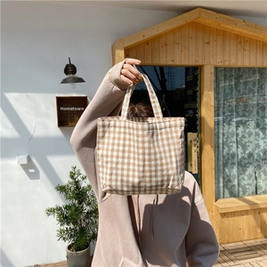 Detail of the brown checkered canvas tote bag with sturdy double handles in daily use