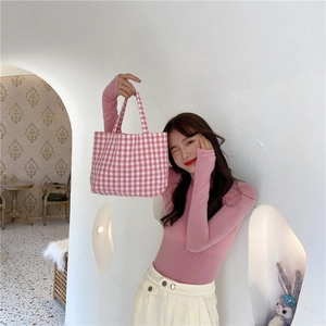 Pink checkered cotton linen lunch tote bag held by a model in a bright interior setting