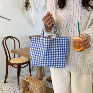 Blue and white checkered cotton linen bento bag shown in a cozy cafe setting