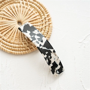 Detail view of marble pattern acetate spring hair clip on a woven lifestyle prop