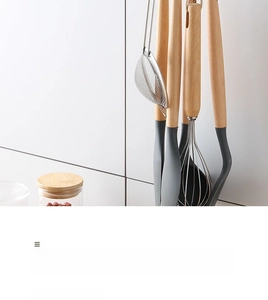 Detail of wall-mounted kitchen utensils with wooden handles and grey silicone heads