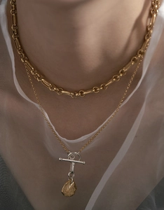 Detail of layered gold bold chain necklace with toggle clasp and hammered organic pendant