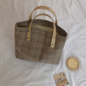 Detail of checkered canvas tote bag with leather handles and metallic rivet fasteners
