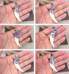 Close-up of resin wolf tooth pendants with vintage silver animal head engravings