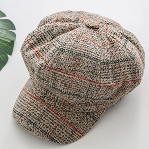 Detail of grey woolen octagonal newsboy cap showing red and black plaid fabric texture