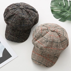 Close-up of retro newsboy caps in brown and apricot plaid wool fabric textures