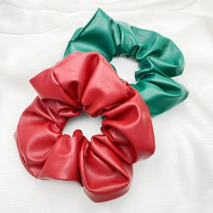Detail view of red and dark green leather scrunchies showing rich premium texture