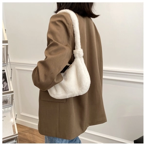 Close-up of fluffy white faux fur crossbody bag worn over a stylish brown blazer jacket