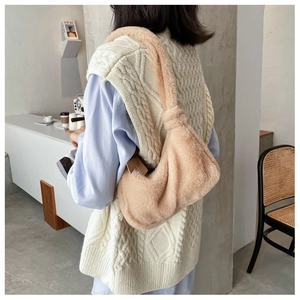 Close-up of light brown faux fur shoulder bag with knotted handle detail on shoulder