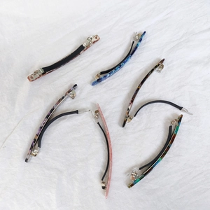 Close-up of 10cm acetate hair clips with marble texture on white fabric background