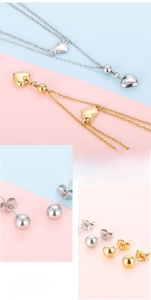 Detail view of gold and silver heart necklaces and round stud earrings set in minimalist style
