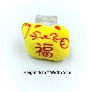 Gros plan d'un pendentif chat porte-bonheur de 4cm avec broderie Fu rouge sur jaune
