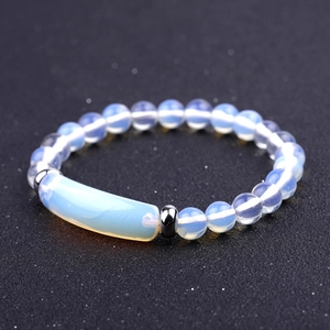 Macro shot of iridescent opal beaded bracelet with a curved rectangle bar on black fabric