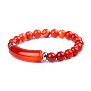 Close-up of a polished red agate bracelet featuring round beads and a smooth bar charm