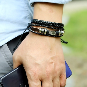 Detail of multi-layer hand-woven leather bracelet with wing charm and adjustable drawstring