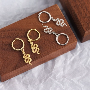 Irregular textured gold and silver snake earrings with hoop dangles on dark wood