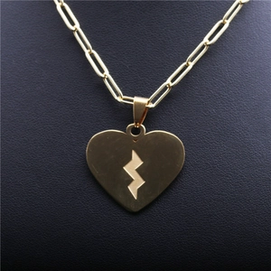 Gold stainless steel paperclip necklace with lightning bolt heart pendant on dark surface
