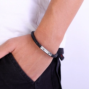 Close-up of a black braided leather bracelet with a silver magnetic clasp on a male wrist