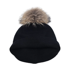 Détail d'un bonnet en maille noire avec un pompon moelleux et une texture à revers