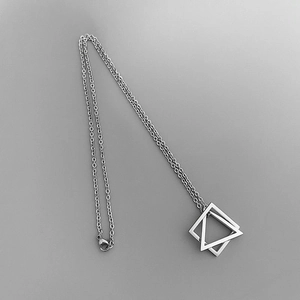 Detailed close-up of interlocking silver triangle pendants on a geometric chain necklace