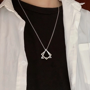 Close-up of a silver geometric interlocking triangle pendant necklace worn by a model