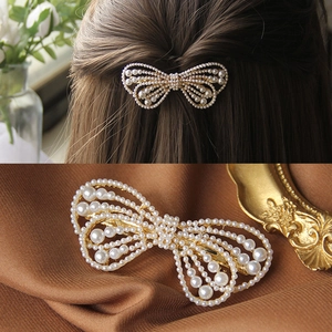 Elegant rhinestone bow hair clip with faux pearls for women on brown silk background
