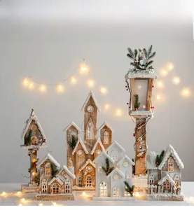 Close-up of lighted miniature wooden Christmas village with snow coating and warm LED lights