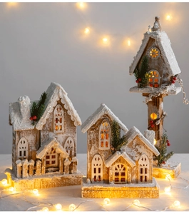Detail of illuminated wooden Christmas house ornaments with warm LED lights and faux snow