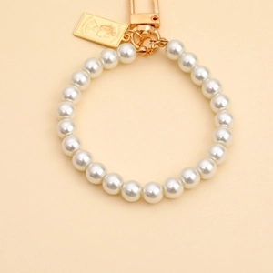 Detail of a pearl bead keychain with a vintage golden Queen Elizabeth II portrait tag.