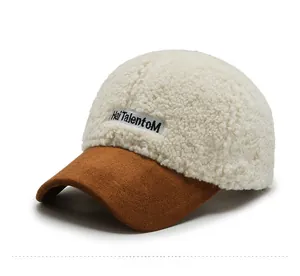 Detail of white lambswool baseball cap with brown suede brim and embroidered logo tag
